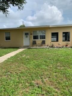 A single-story house with yellow siding, a white front door, and a grassy front yard — 8274 BUMFORD AVENUE, NORTH PORT, FL