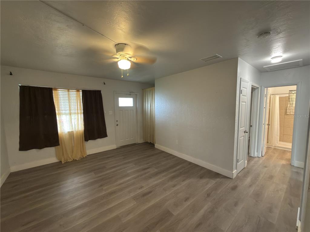 A living room features light wood-look flooring, a ceiling fan, and an adjacent bathroom doorway — 8274 BUMFORD AVENUE, NORTH PORT, FL