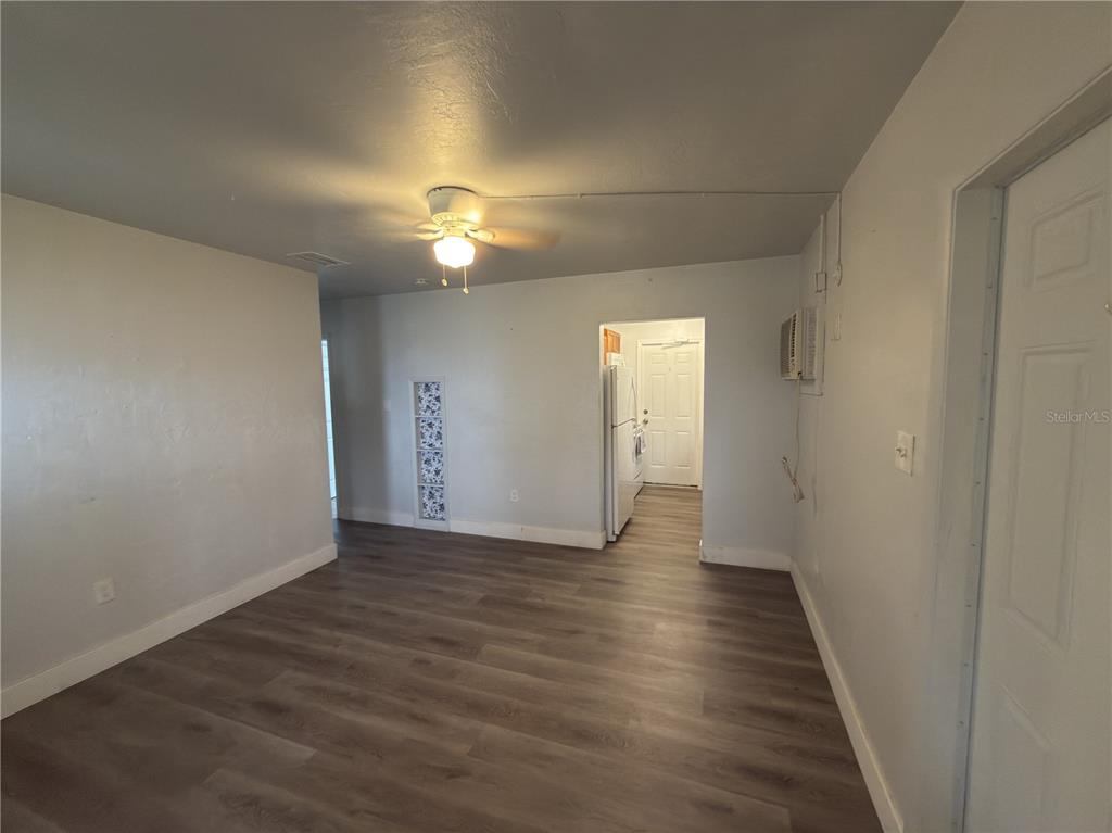 An interior view of a room with wood-look flooring, a ceiling fan, and a doorway — 8274 BUMFORD AVENUE, NORTH PORT, FL