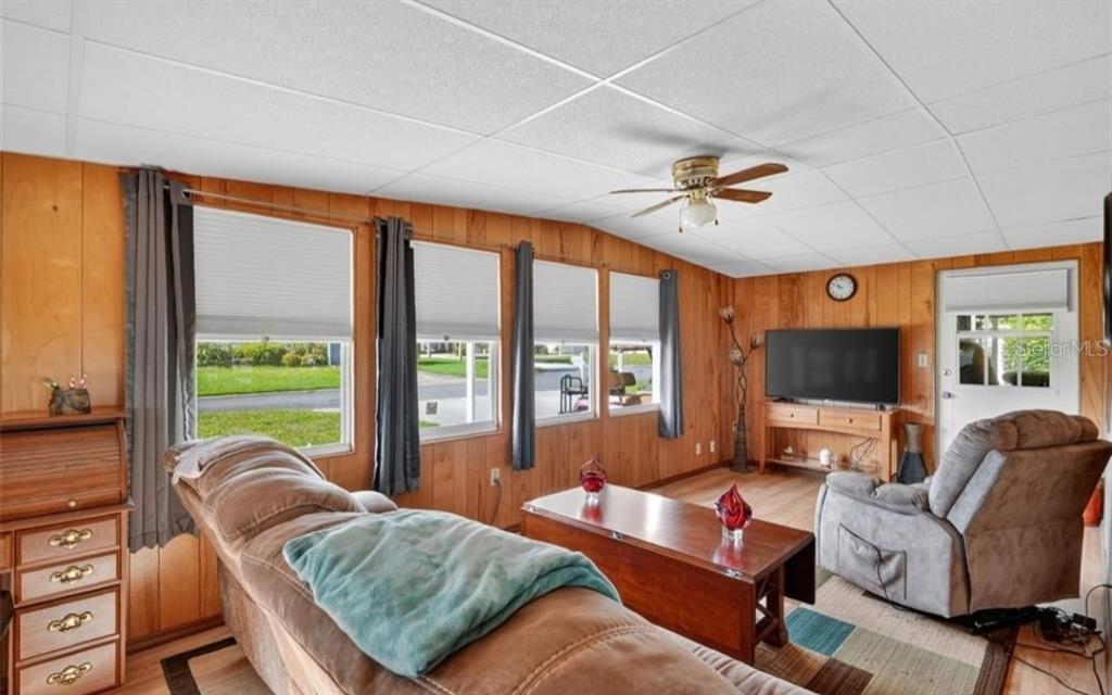 A living room features wood-paneled walls, a drop ceiling, multiple windows, and a ceiling fan — 11905 LINDA AVENUE, TAVARES, FL
