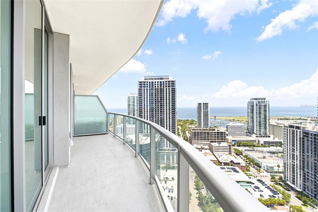 A high-rise balcony with a glass railing overlooks a city skyline and the ocean — 400 CENTRAL AVENUE UNIT 2901, ST PETERSBURG, FL
