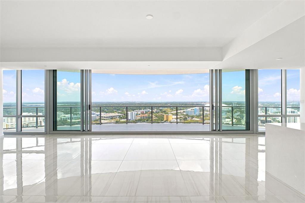 A bright, empty room with white tile floors features floor-to-ceiling windows overlooking a city skyline — 400 CENTRAL AVENUE UNIT 2901, ST PETERSBURG, FL