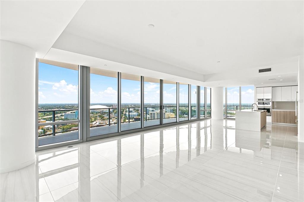 A bright, open-concept living area with floor-to-ceiling windows, white tile floors, and a modern kitchen — 400 CENTRAL AVENUE UNIT 2901, ST PETERSBURG, FL