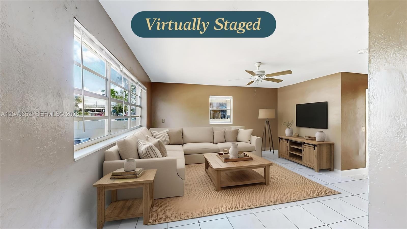 A virtually staged living room features a beige sectional, wooden furniture, and white tile flooring — 2760 NW 58th St, Miami FL 33142, MIAMI, FL