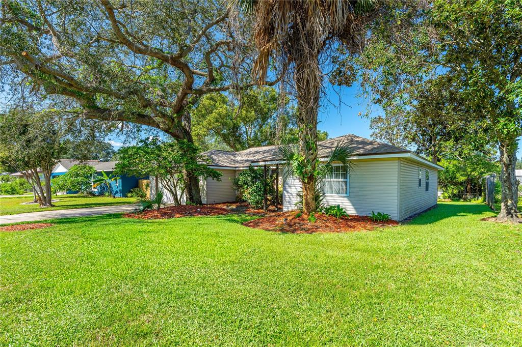 A single-story house with light-colored siding stands on a grassy lot under large trees — 693 REILLYS ROAD, PORT ORANGE, FL