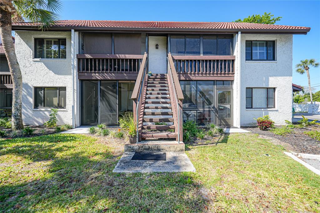 A two-story apartment building features a central wooden staircase leading to an upper balcony — 1636 STICKNEY POINT ROAD UNIT 36-201, SARASOTA, FL