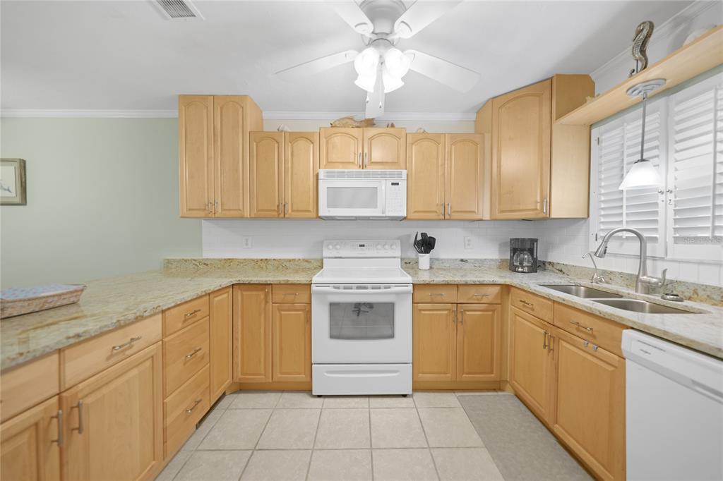 A kitchen with light wood cabinets, granite countertops, white appliances, and tiled flooring — 1636 STICKNEY POINT ROAD UNIT 36-201, SARASOTA, FL