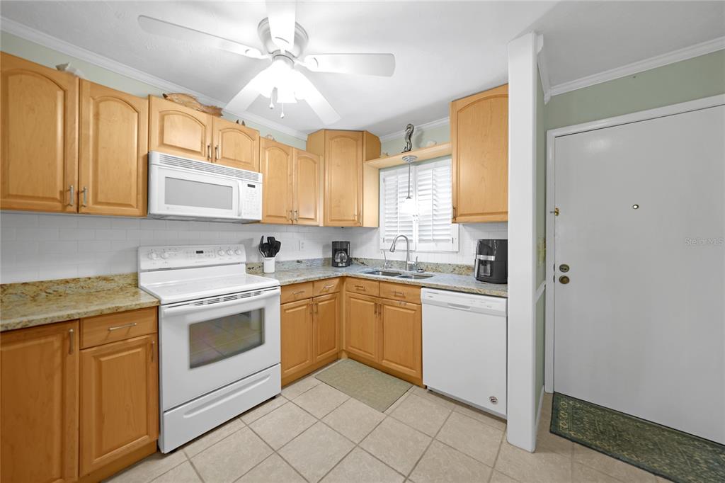 A kitchen features light wood cabinets, granite countertops, white appliances, and tiled flooring — 1636 STICKNEY POINT ROAD UNIT 36-201, SARASOTA, FL