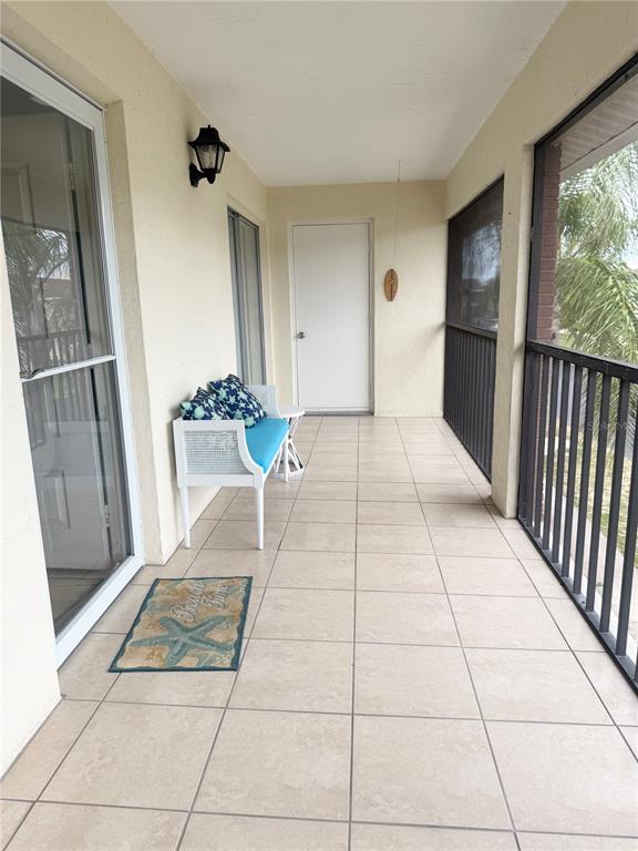 A covered balcony features tiled flooring, a white bench, and a screened-in railing — 1531 PLACIDA ROAD UNIT 202, ENGLEWOOD, FL