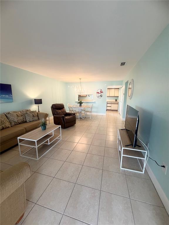 A living room with light blue walls, tile flooring, a sofa, a recliner, and a dining area — 1531 PLACIDA ROAD UNIT 202, ENGLEWOOD, FL