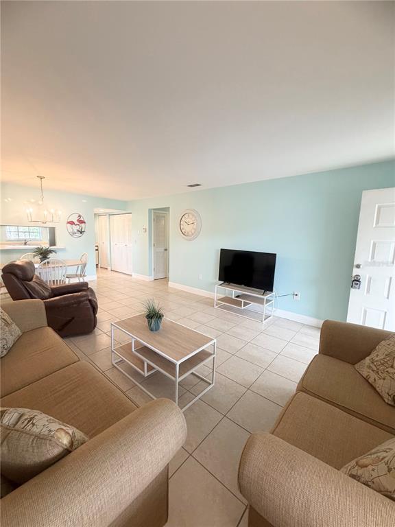 A living room features light blue walls, tile flooring, two sofas, and a television stand — 1531 PLACIDA ROAD UNIT 202, ENGLEWOOD, FL