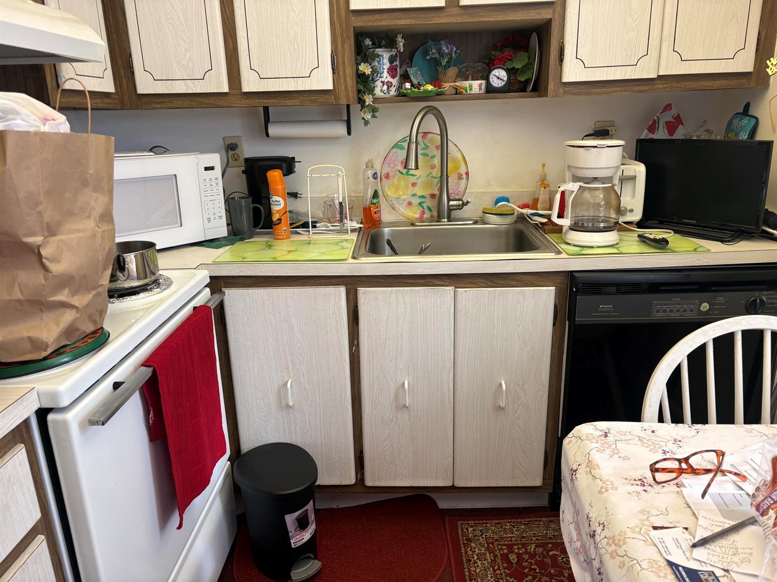 A kitchen features white wood-grain cabinets, a stainless steel sink, and various countertop appliances — 862 Normandy R Trail # R, Delray Beach FL 33484, DELRAY BEACH, FL