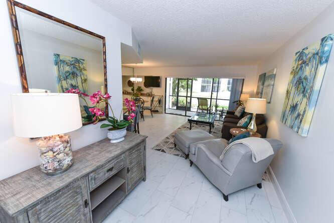 A living room with a gray armchair, a wooden console table, and a large mirror — 1605 S Us Highway 1 # B105, Jupiter FL 33477, JUPITER, FL