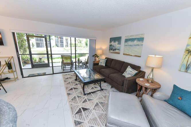A living room with a brown sofa, glass coffee table, and a view of a patio — 1605 S Us Highway 1 # B105, Jupiter FL 33477, JUPITER, FL