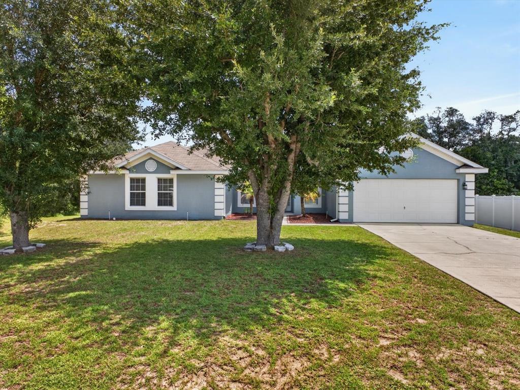 A single-story house with a blue exterior, a two-car garage, and large trees in front — 417 RIO GRANDE COURT, KISSIMMEE, FL