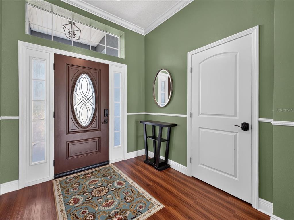 An entryway features green walls, white trim, a dark wood front door, and hardwood flooring — 417 RIO GRANDE COURT, KISSIMMEE, FL