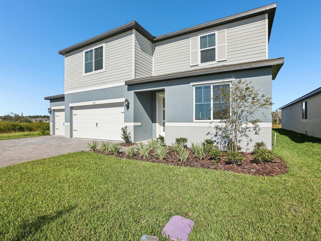 A two-story house with a gray stucco and siding exterior, a garage, and a lawn — 1922 COOLRIDGE PLACE, ZEPHYRHILLS, FL