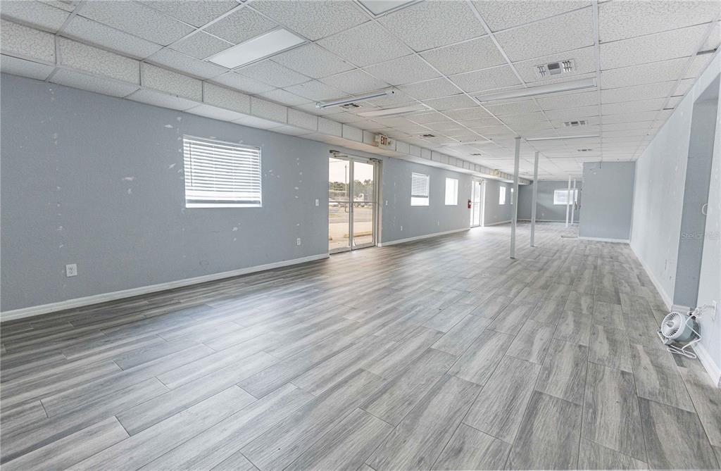 An empty commercial space features light gray wood-look flooring, light blue walls, and drop ceilings — 700 N MAIN STREET, WILDWOOD, FL