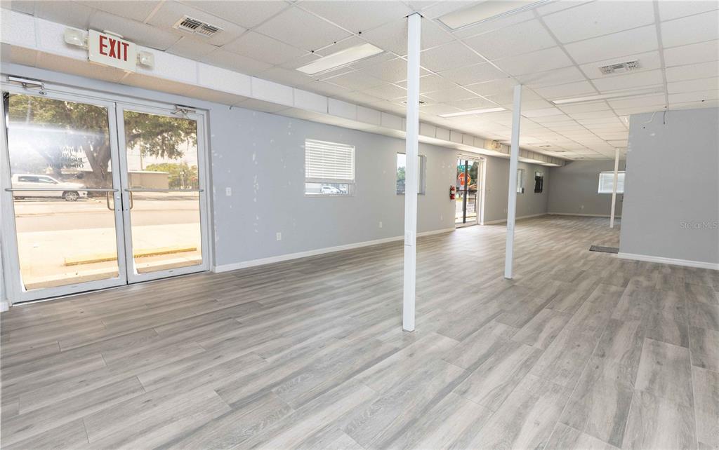 An empty commercial space features light gray wood-look flooring, white walls, and a drop ceiling — 700 N MAIN STREET, WILDWOOD, FL
