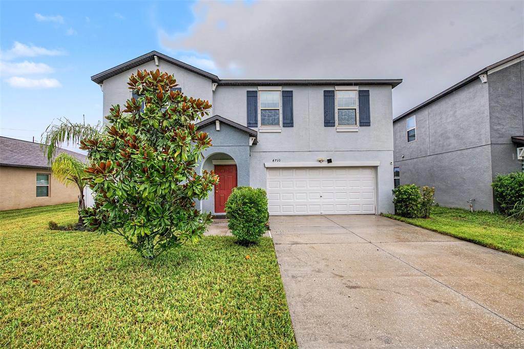 A two-story house with a light gray exterior, a red front door, and a concrete driveway — 4710 WILD SENNA BOULEVARD, TAMPA, FL