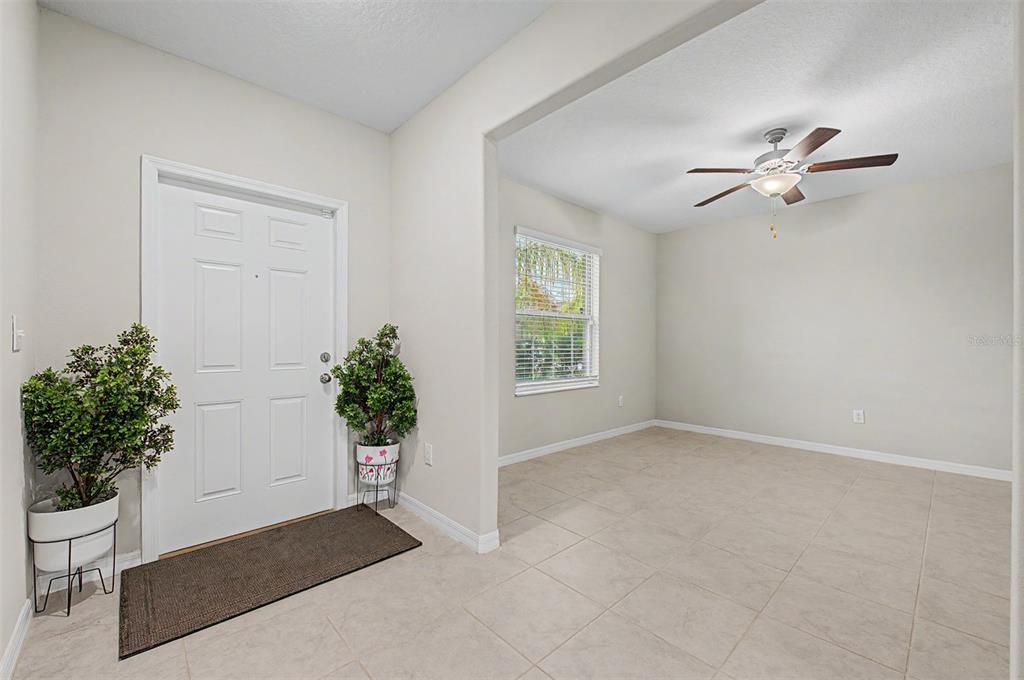 An entryway with a white door and a tiled room featuring a ceiling fan — 4710 WILD SENNA BOULEVARD, TAMPA, FL