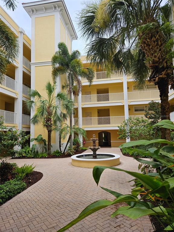 A courtyard features a stone fountain, palm trees, and a yellow multi-story building — 255 W END DRIVE UNIT 4308, PUNTA GORDA, FL