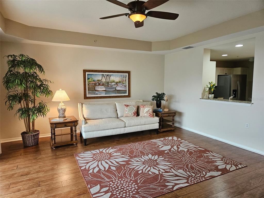 A living room features a beige sofa, a floral rug, and a ceiling fan — 255 W END DRIVE UNIT 4308, PUNTA GORDA, FL
