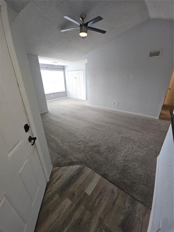 An entryway with wood-look flooring leads into a carpeted living room with a ceiling fan — 5160 CONROY ROAD UNIT 1437, ORLANDO, FL
