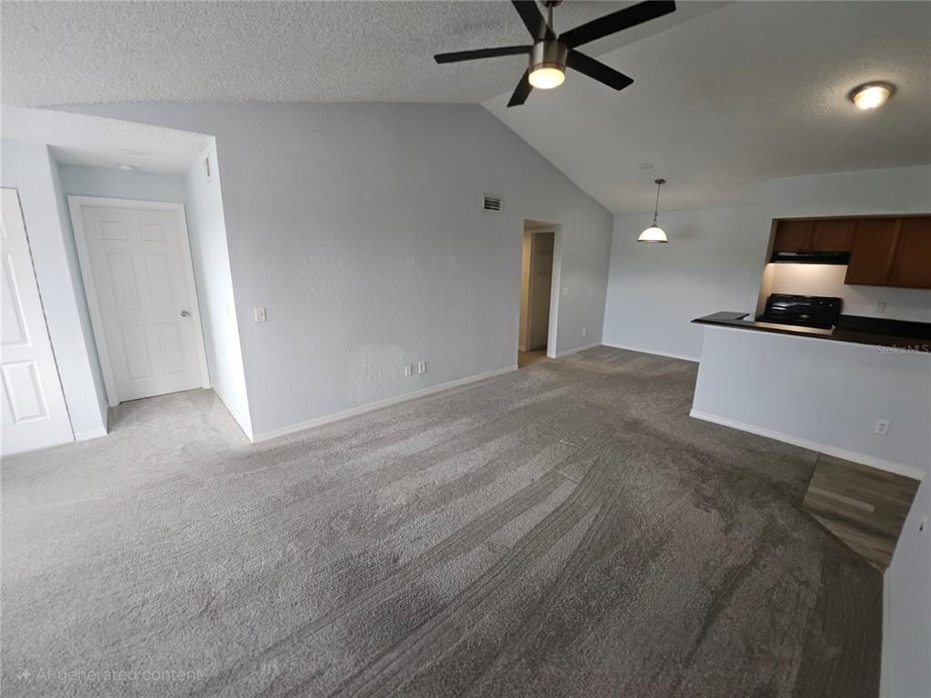 A living room with gray carpeting, a vaulted ceiling, a ceiling fan, and an open kitchen — 5160 CONROY ROAD UNIT 1437, ORLANDO, FL