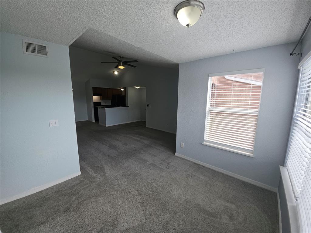 A carpeted living room leads into a kitchen with a breakfast bar and ceiling fan — 5160 CONROY ROAD UNIT 1437, ORLANDO, FL
