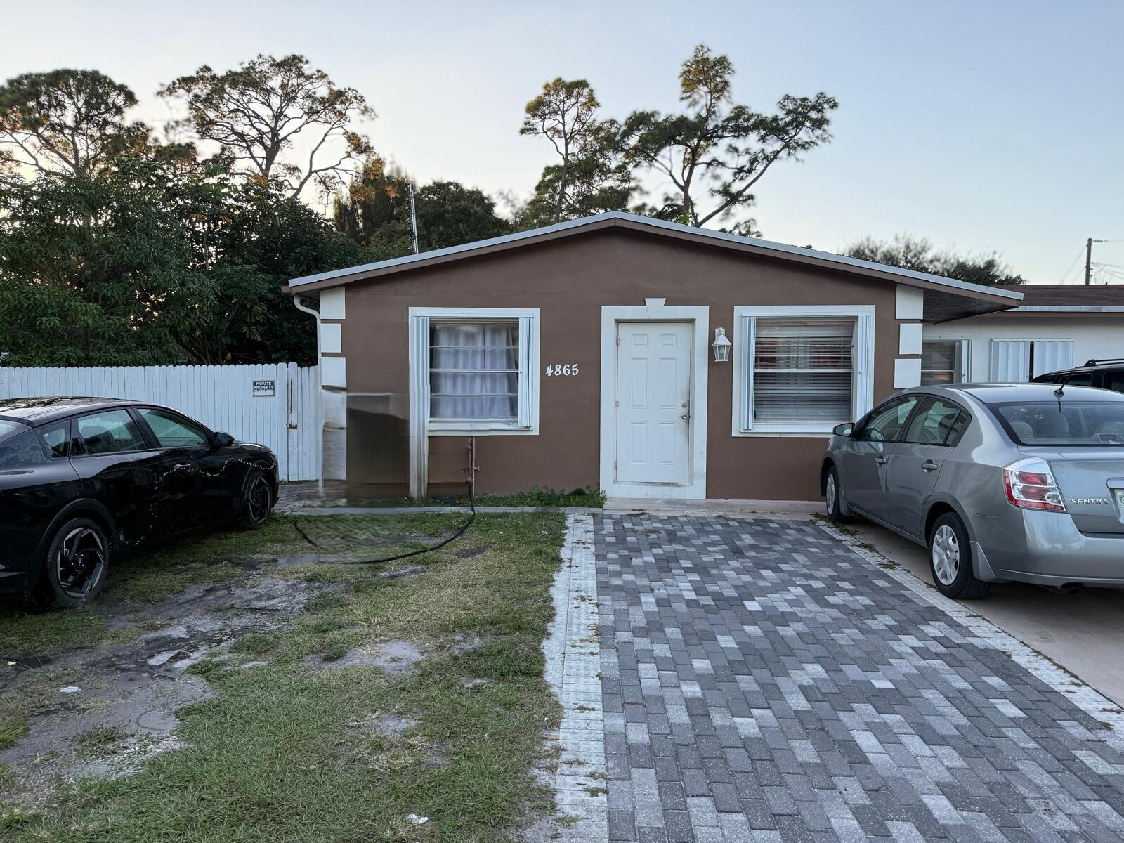 A brown single-story house with a white door, two windows, and a paved driveway — 4865 Dell Avenue, Lake Worth FL 33461, LAKE WORTH, FL