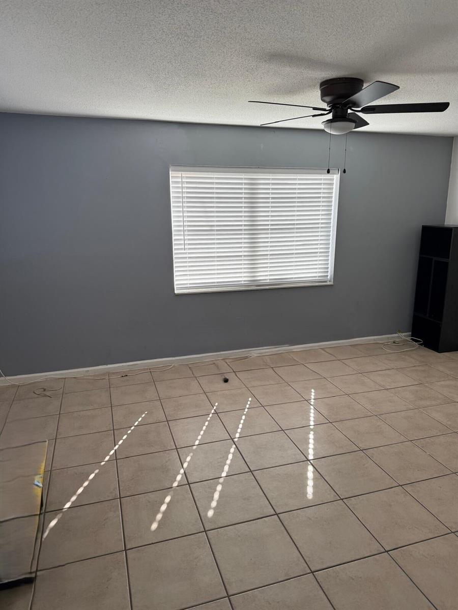 A room with gray walls, beige tile flooring, a window with blinds, and a ceiling fan — 4865 Dell Avenue, Lake Worth FL 33461, LAKE WORTH, FL