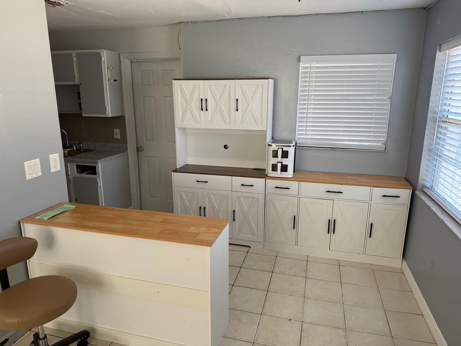 A kitchen area features white cabinets with X-pattern doors, wood countertops, and light tile flooring — 4865 Dell Avenue, Lake Worth FL 33461, LAKE WORTH, FL