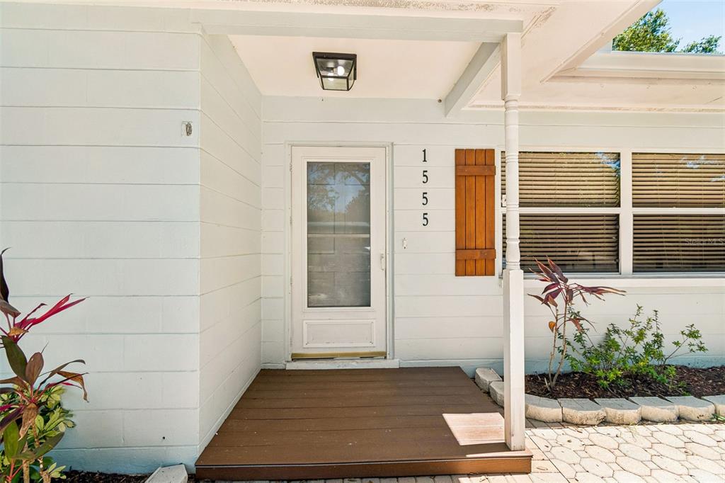 A white front door with a wooden shutter and a small deck entrance — 1555 MAGNOLIA DRIVE, CLEARWATER, FL