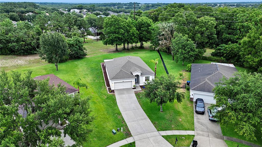 An aerial view shows three suburban houses surrounded by large green lawns and mature trees — 5708 RUTHERFORD ROAD, MOUNT DORA, FL