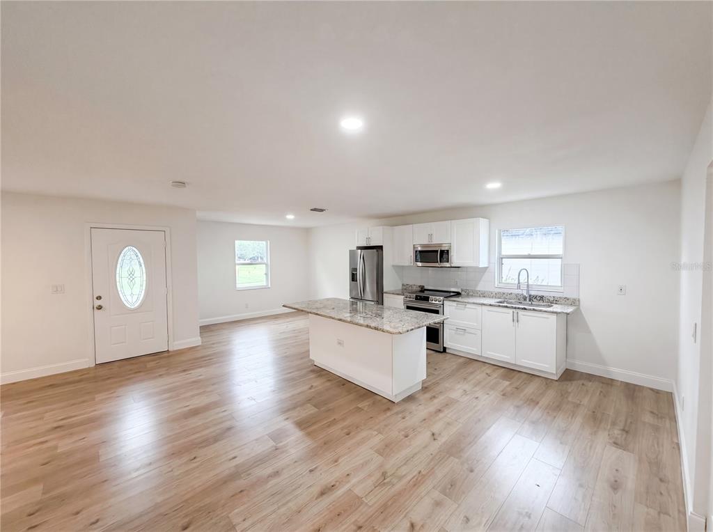 A kitchen with white cabinets, granite countertops, and a central island opens to a living area — 845 40TH AVENUE S, ST PETERSBURG, FL