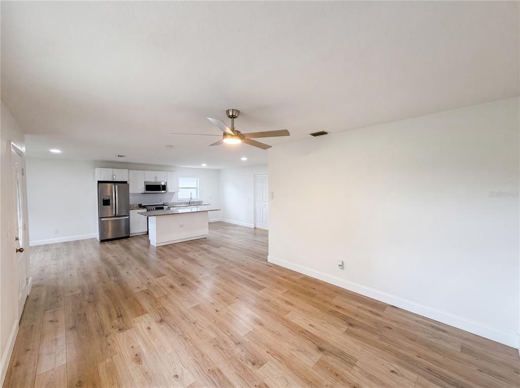 An open-concept kitchen and living area features light wood-look flooring and white cabinetry — 845 40TH AVENUE S, ST PETERSBURG, FL