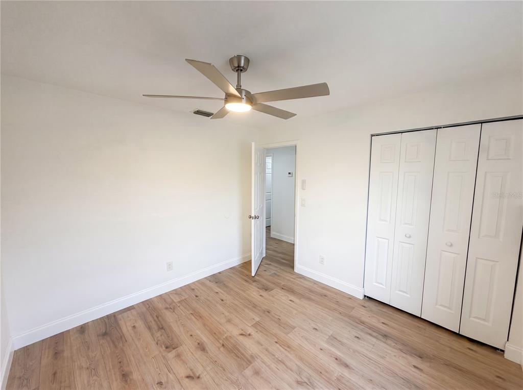 A bedroom with light wood-look flooring, white walls, a ceiling fan, and a white closet — 845 40TH AVENUE S, ST PETERSBURG, FL
