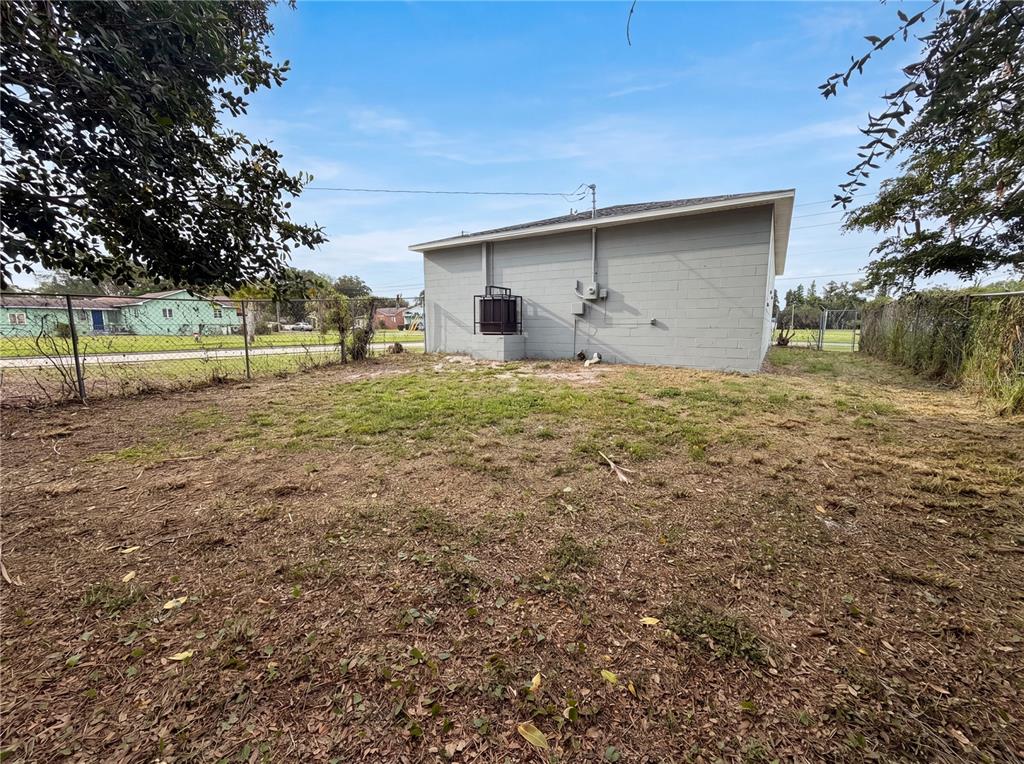 A gray concrete block building stands in a fenced, sparsely grassed backyard — 845 40TH AVENUE S, ST PETERSBURG, FL