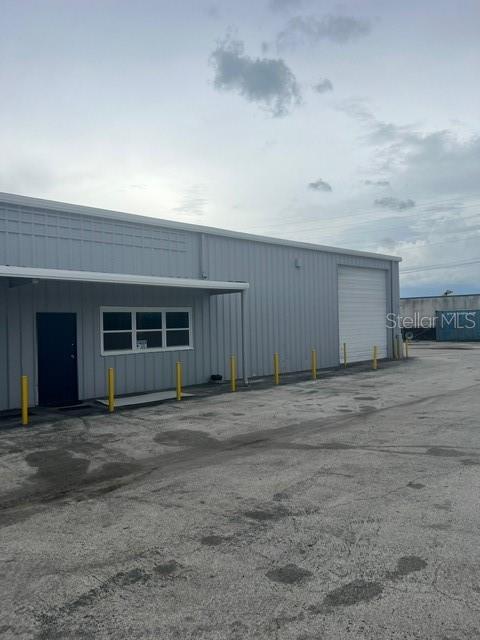 A gray metal industrial building features a dark door, a window, and a roll-up door — 2525 CLARCONA ROAD, APOPKA, FL