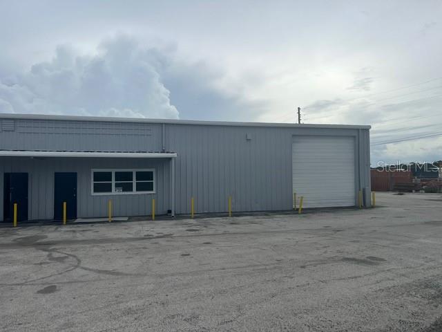 A gray metal industrial building features a roll-up door and a small entrance — 2525 CLARCONA ROAD, APOPKA, FL