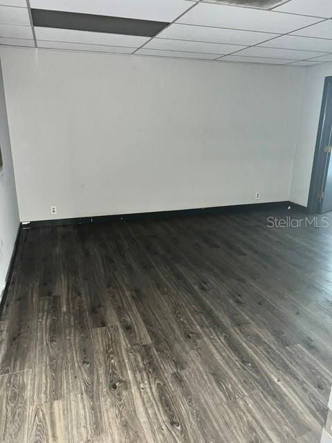 An empty room features gray wood-look flooring, white walls, and a drop ceiling — 2525 CLARCONA ROAD, APOPKA, FL
