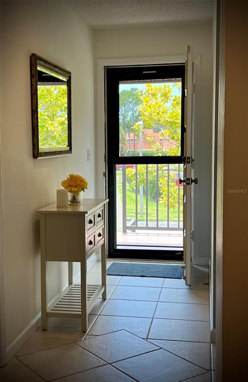An entryway with tiled floors, a small white console table, a mirror, and a door — 4606 WEYBRIDGE UNIT 26, SARASOTA, FL