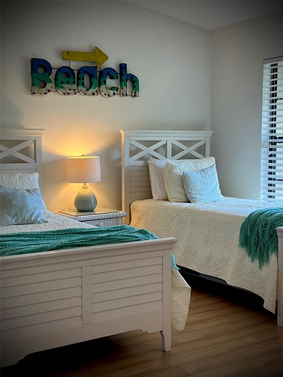 A living room features a woven ottoman, a dark sofa, and a balcony with palm trees — 4606 WEYBRIDGE UNIT 26, SARASOTA, FL