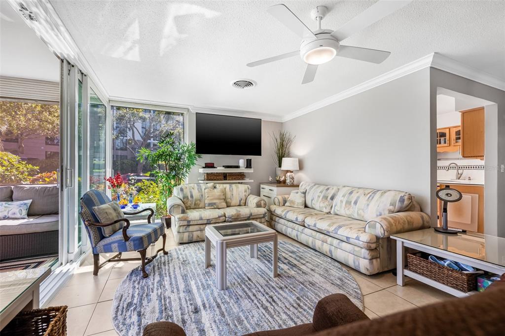 A living room with a ceiling fan, patterned sofas, a round rug, and sliding glass doors — 615 10TH AVENUE NE UNIT 1, ST PETERSBURG, FL