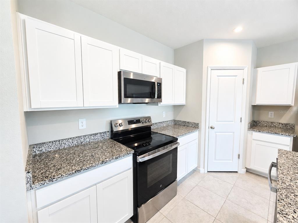 A kitchen features white cabinets, granite countertops, and stainless steel appliances — 810 172ND COURT E, BRADENTON, FL