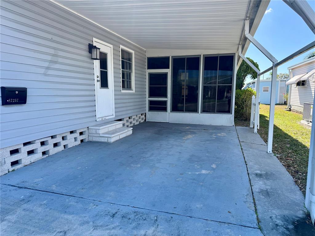 A concrete carport with a screened-in porch and light blue siding on a residential home — 82257 3RD AVENUE N UNIT 257, PINELLAS PARK, FL
