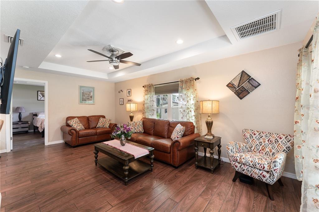 A living room features brown leather sofas, a patterned armchair, and dark wood flooring — 3241 TROPICAIRE BOULEVARD, NORTH PORT, FL
