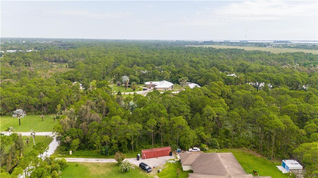 An aerial view shows a house surrounded by dense forest with a red storage container — FORT PIERCE, FL