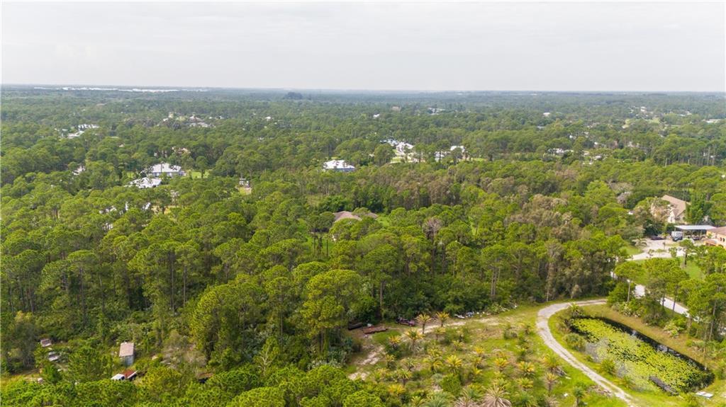 An aerial view shows a wooded residential area with scattered houses and a small pond — FORT PIERCE, FL
